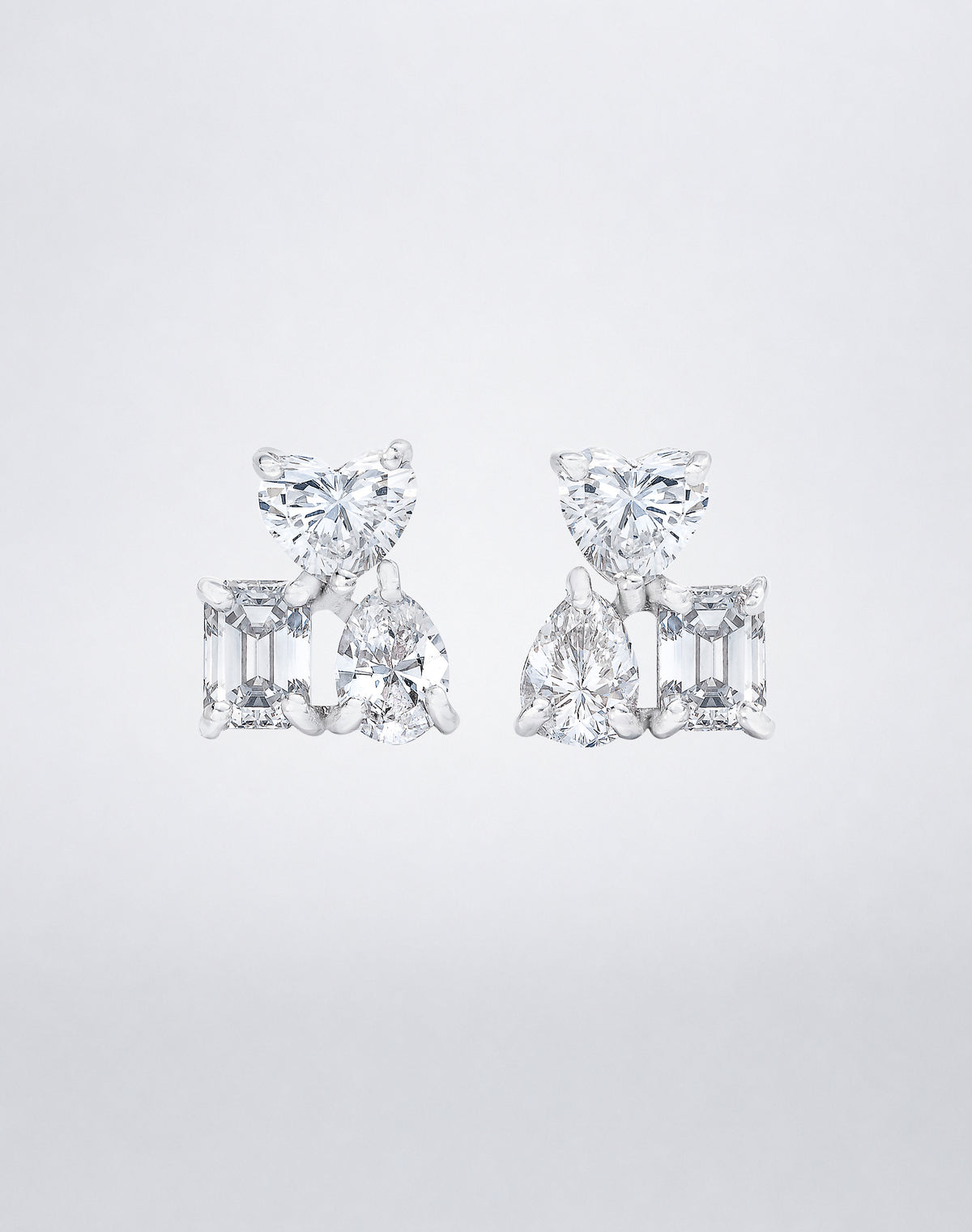 Mindi Mond New York Fancy Cut Cluster Stud Earrings in 18K white gold, heart, emerald and pear-cut diamonds claw-set in a mirrored three-stone cluster