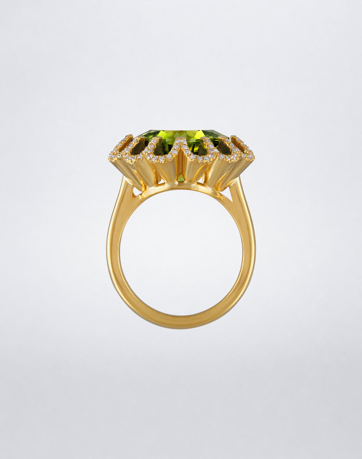 Side view of the Mindi Mond New York FLOATING HUES Mini Peridot and Diamond Ring in 18K yellow gold, highlighting the cushion-cut peridot and iconic elliptical setting.