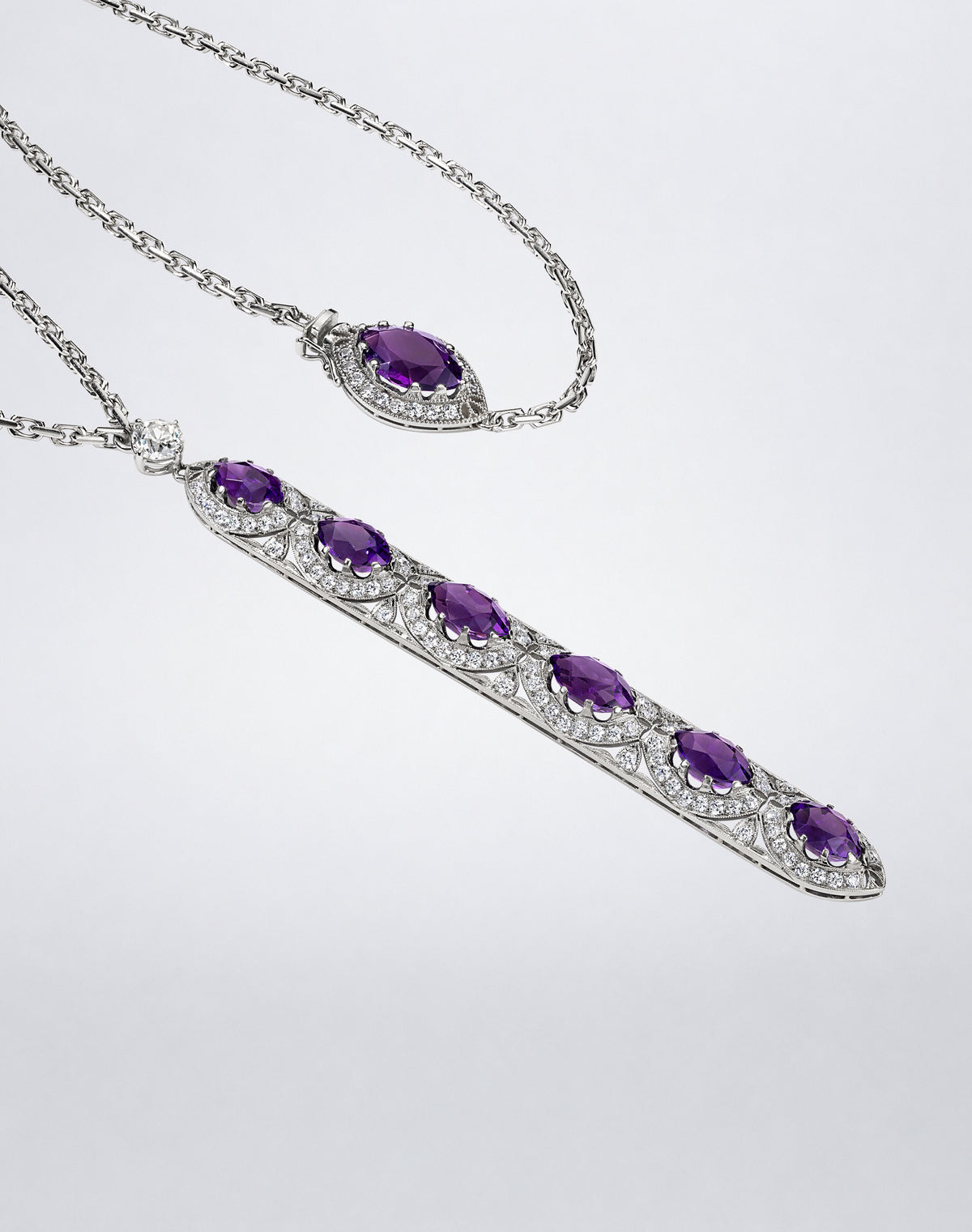 Close-up of an amethyst and diamond sautoir featuring an elongated pendant set with six oval purple amethysts and diamond detailing.