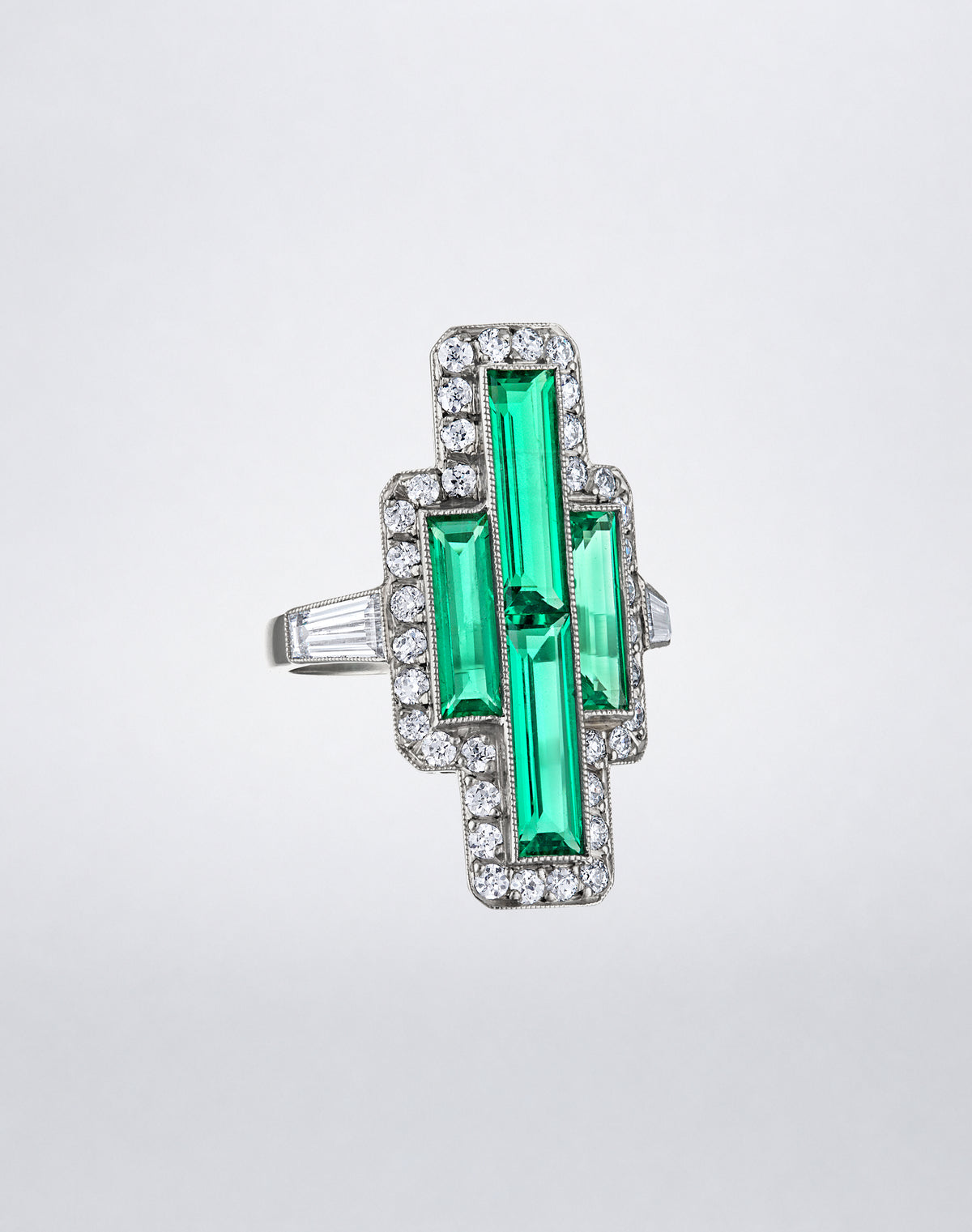 Angled view of the one-of-a-kind Colombian Emerald Tapered Baguette Pointer Ring showing geometric emeralds, round diamonds and tapered baguette side stones.