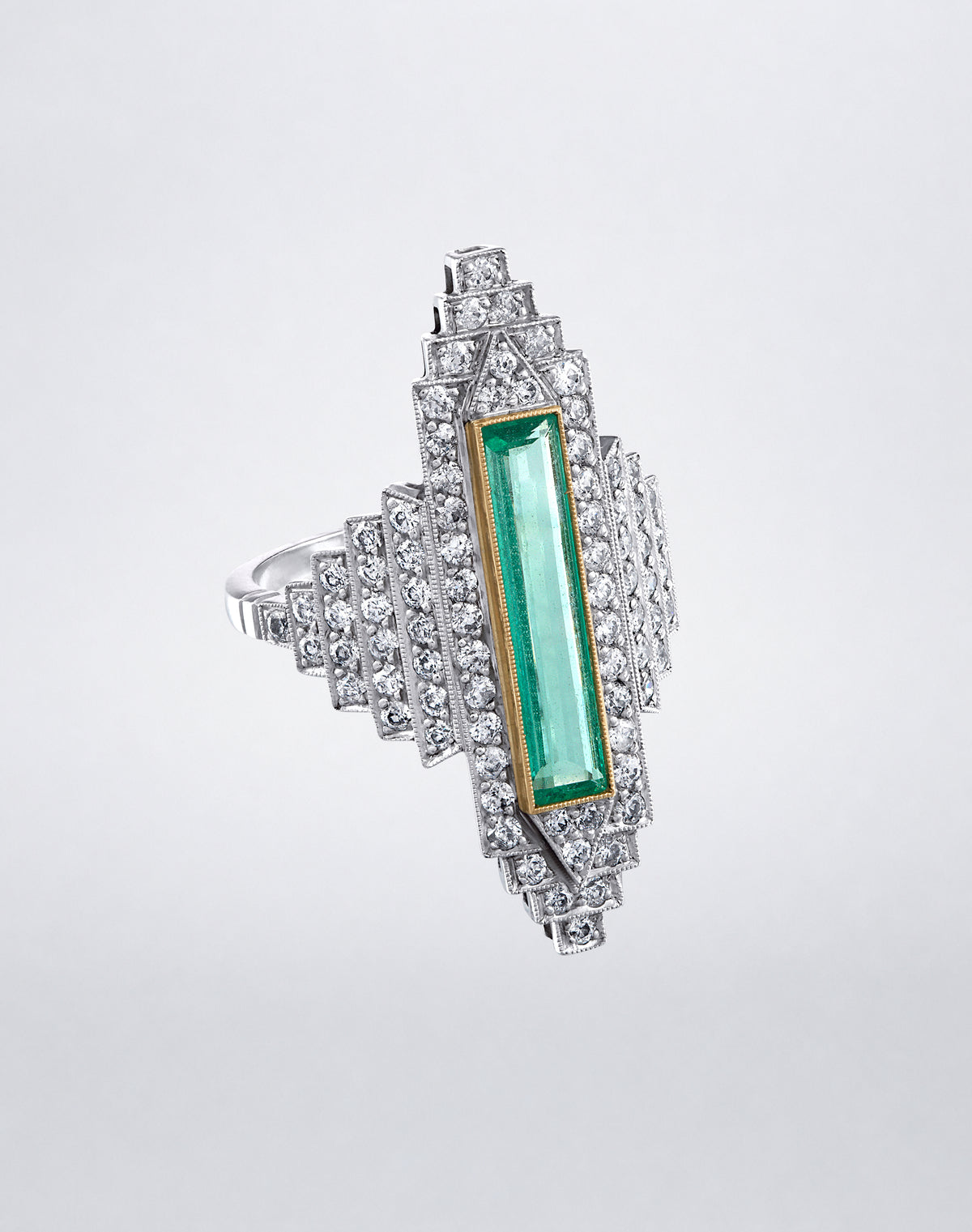 Angled view of the one-of-a-kind Emerald City Ring showing the elongated emerald center and layered diamond-set geometric detailing.