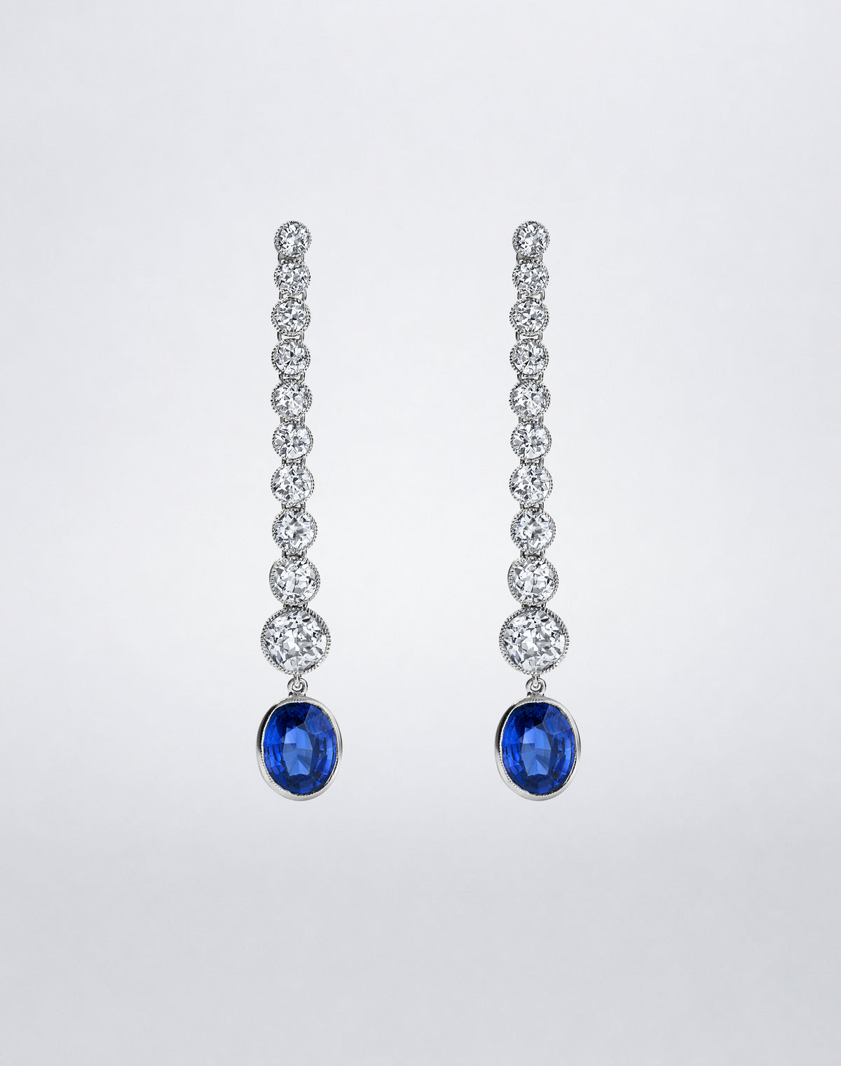 One-of-a-kind Milgrain Diamond and Sapphire Line Earrings featuring graduated round diamonds with milgrain detailing and oval blue sapphire drops.