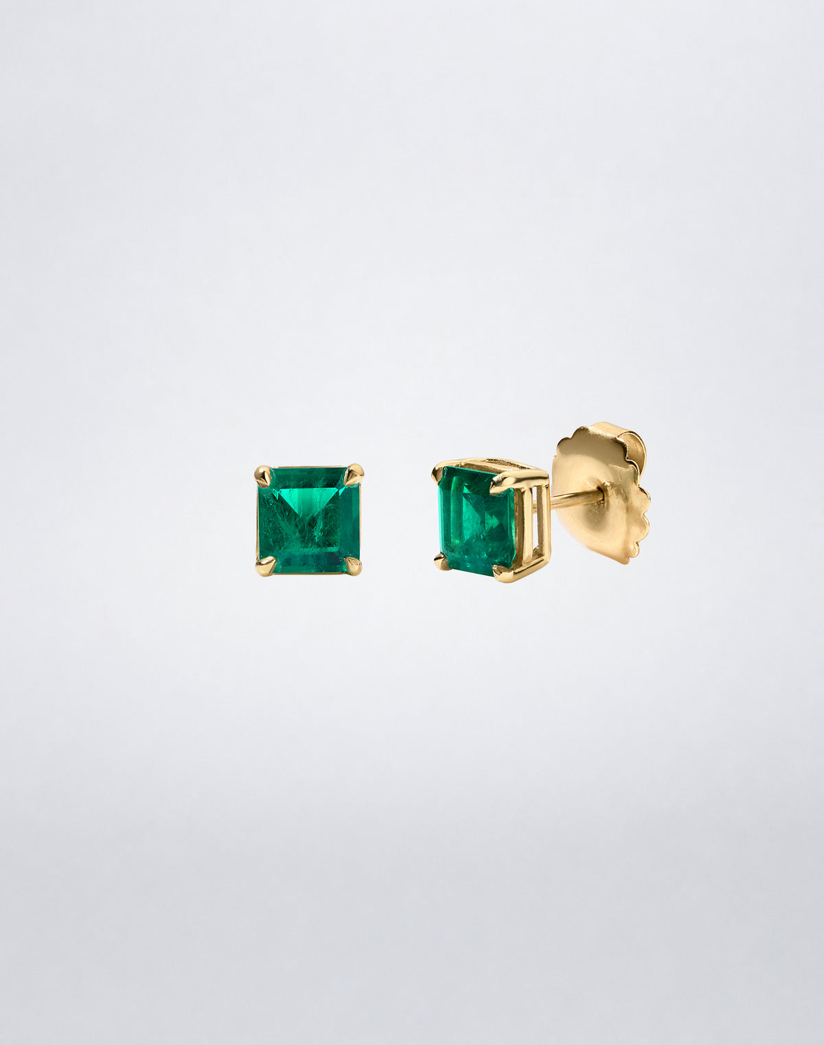 Side view of Mindi Mond New York ICONS Colombian Emerald Stud Earrings in 18K yellow gold, showing the four-prong setting and post closure.