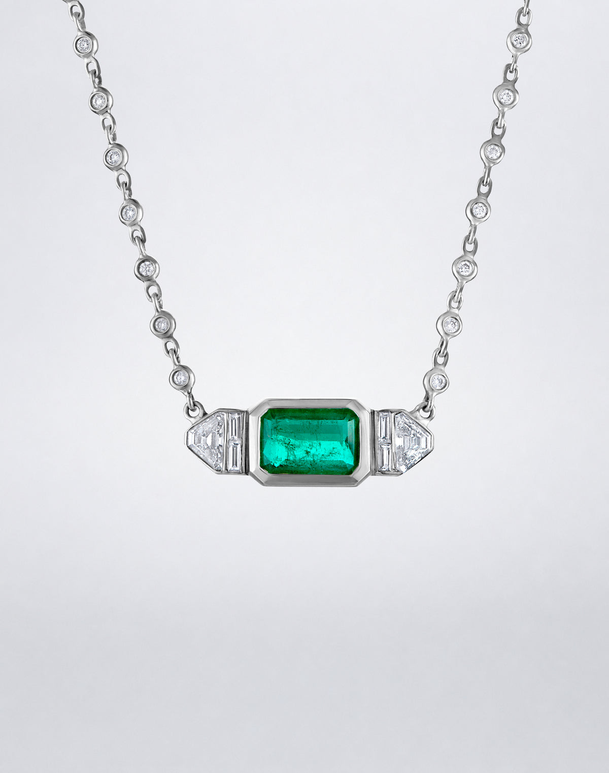 Close-up of an emerald-cut emerald flanked by baguette and trapezoid-cut diamonds on the Mindi Mond New York Trapezoid Necklace.