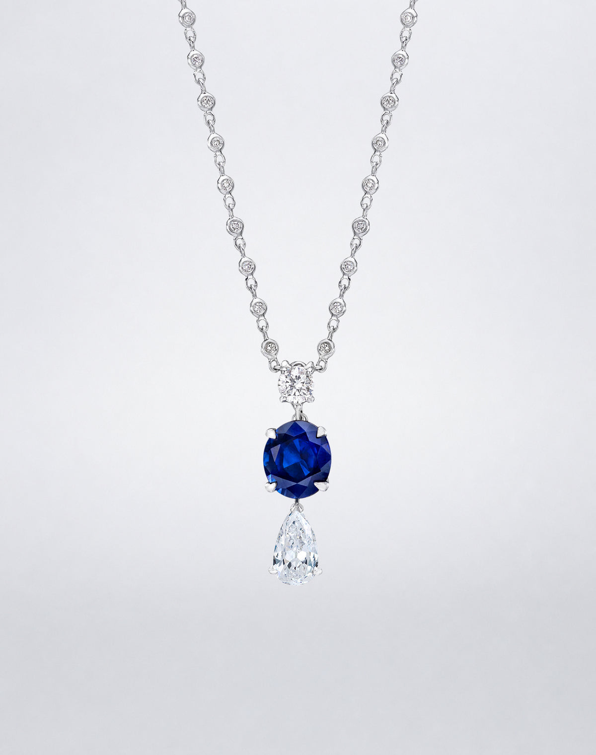 Mindi Mond New York Sapphire Dangling Diamond Pendant Necklace with blue sapphire, round diamond and pear-shaped diamond in 18K white gold.