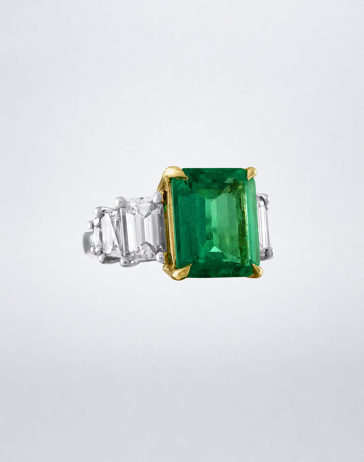 Mindi Mond New York Triple Step Colombian Emerald Ring featuring a Colombian emerald with step-cut diamond sides in gold and platinum, angled view.