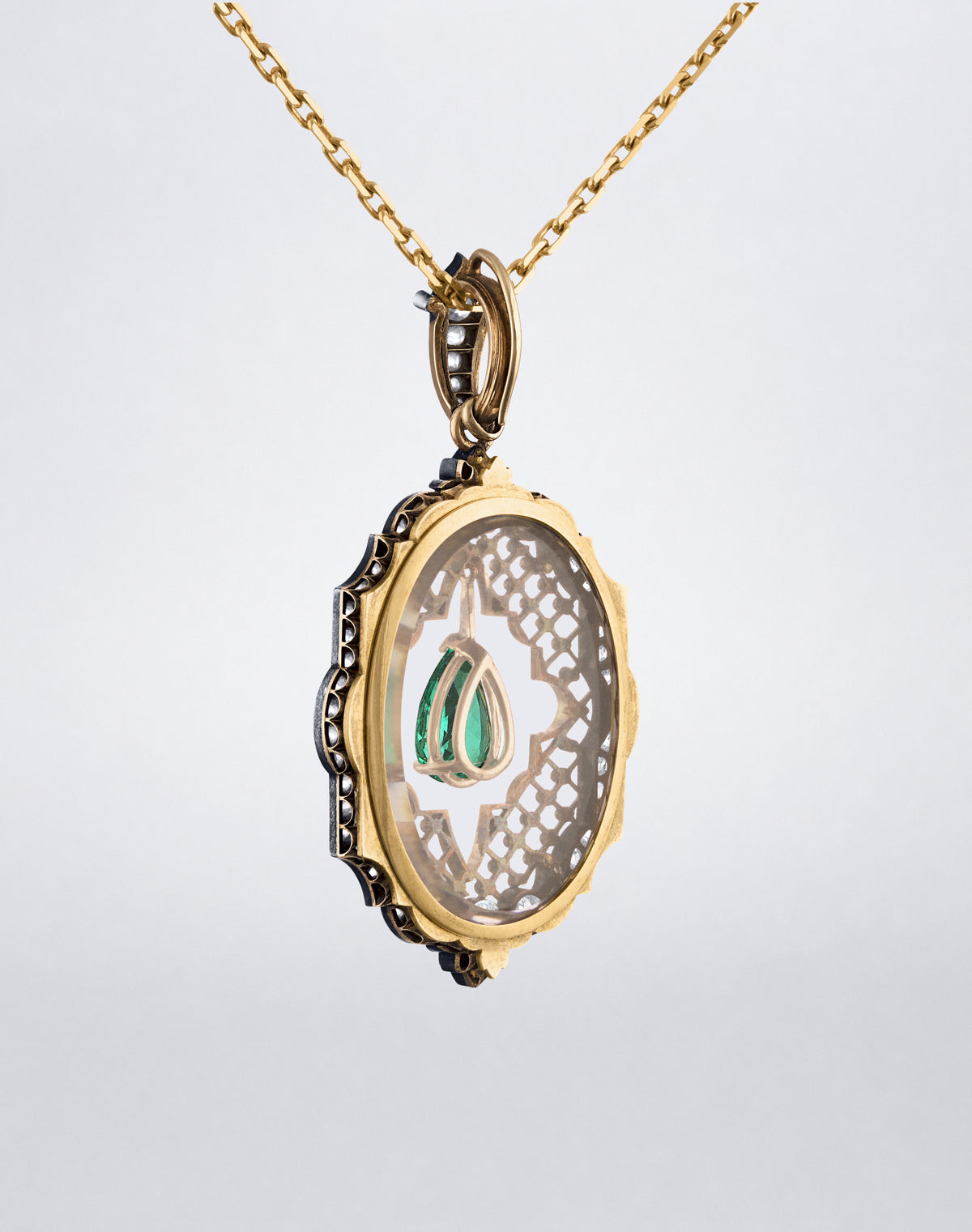 Angled view of the Colombian Emerald and Diamond Locket Necklace showing the dimensional locket setting, suspended pear-shaped emerald and diamond detailing.