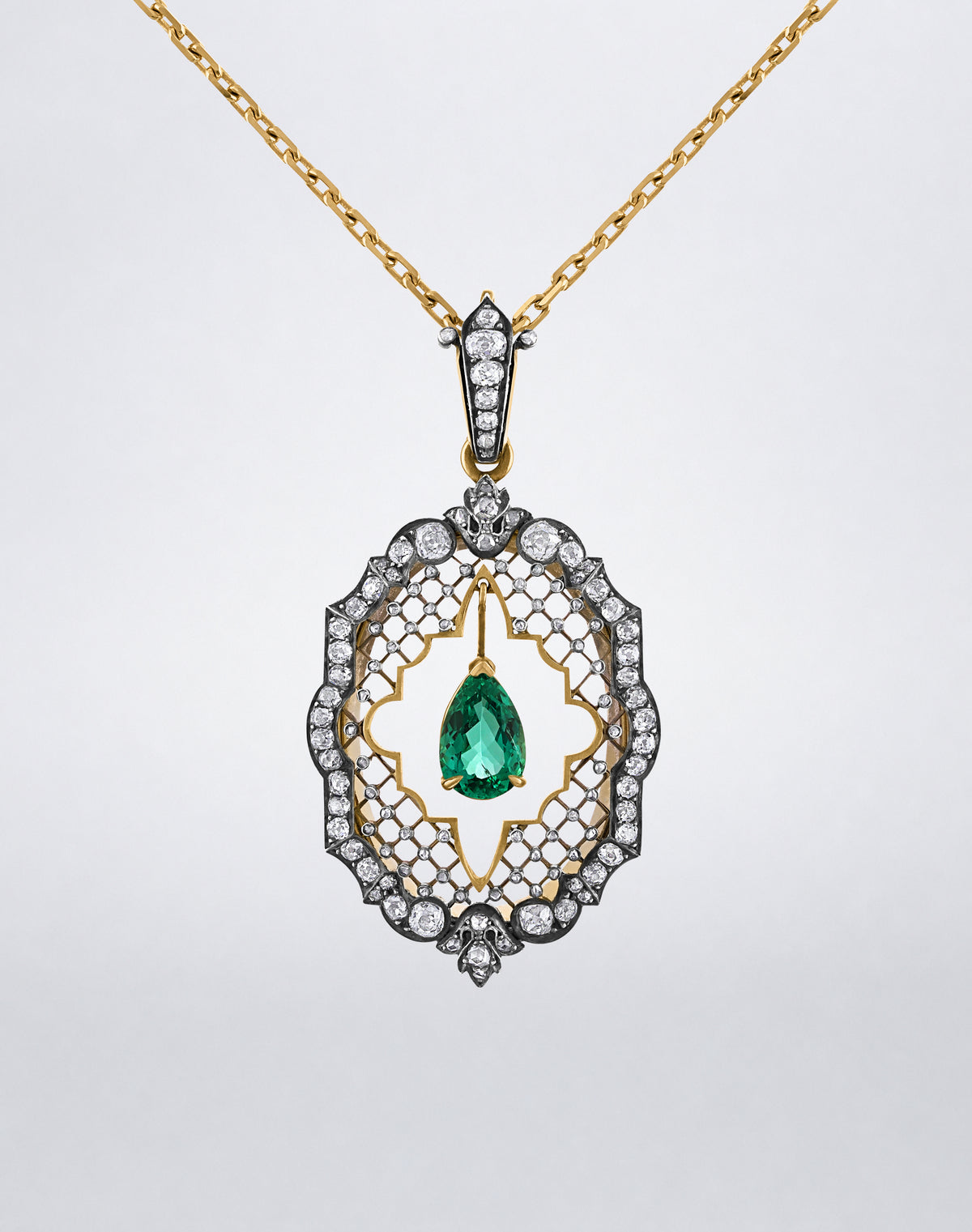 One-of-a-kind Colombian Emerald and Diamond Locket Necklace featuring a pear-shaped Colombian emerald suspended within an ornate diamond-set openwork locket on a yellow gold chain.
