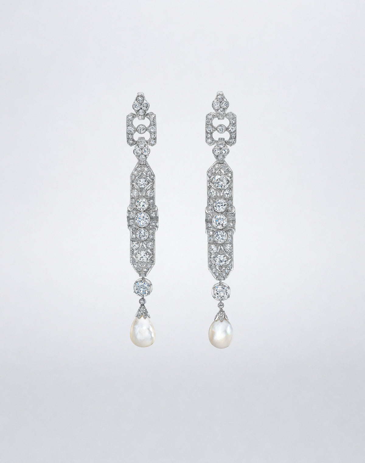 One-of-a-kind Deco Gala Pearl and Diamond Earrings featuring luminous cultured pearl drops suspended from geometric platinum settings adorned with Old Mine cut diamonds.