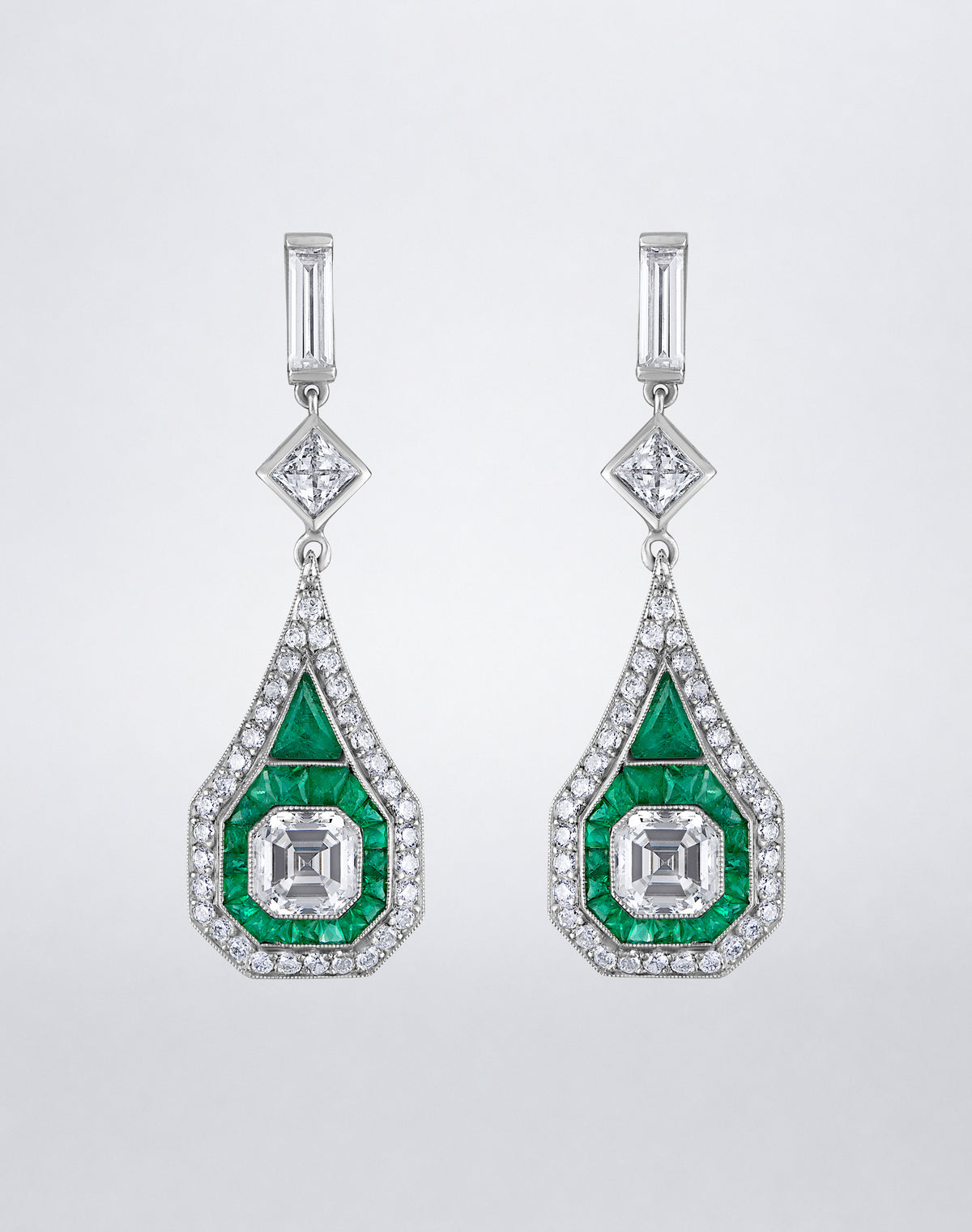 One-of-a-kind Deco Elongated Emerald Drop Earrings featuring geometric emeralds, Asscher-cut center diamonds and diamond-bordered drops in platinum.
