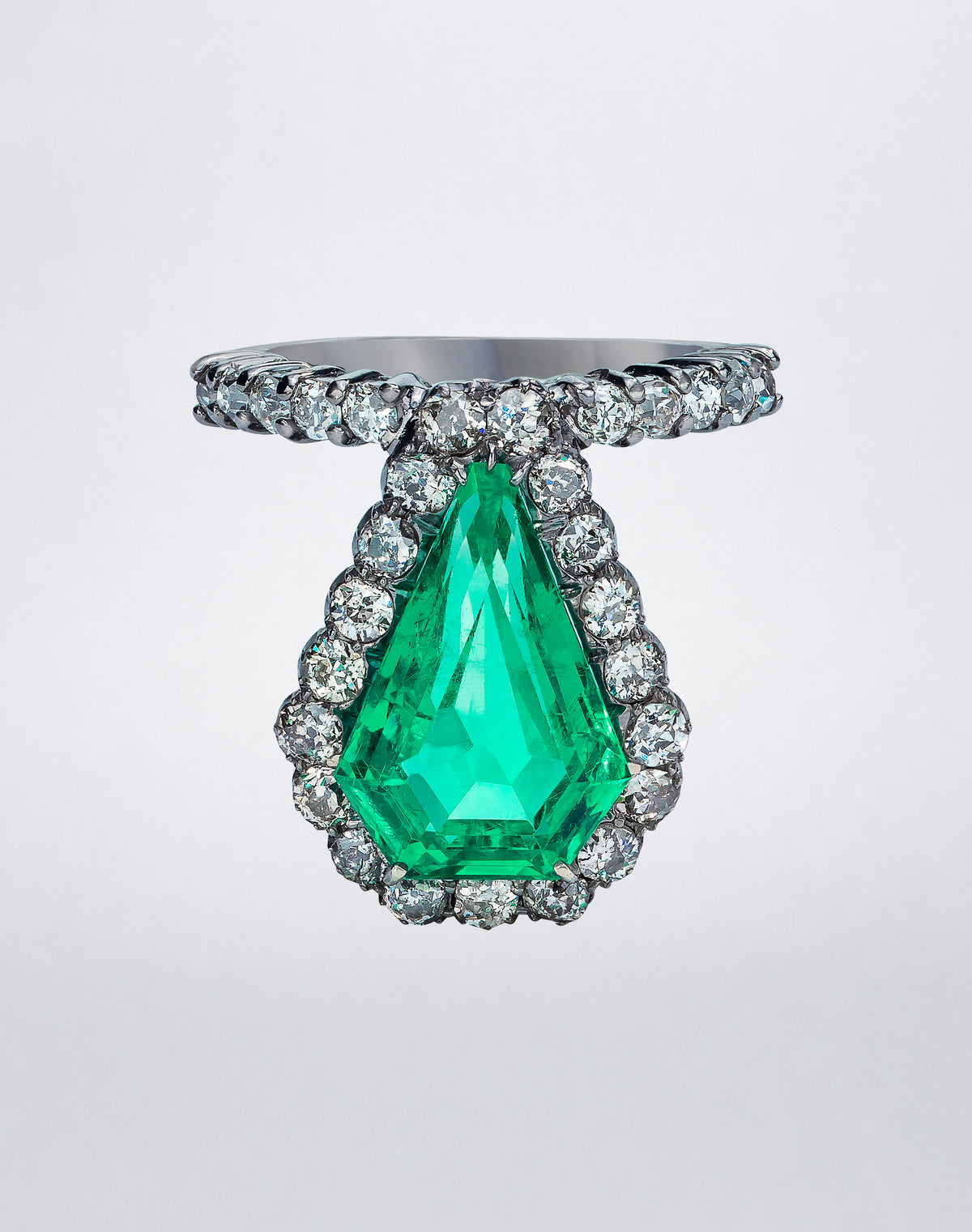One-of-a-kind Emerald and Diamond Shield Ring featuring a shield-cut Colombian emerald set in silver and framed by antique-cut diamonds in rhodium-finished 18K gold.