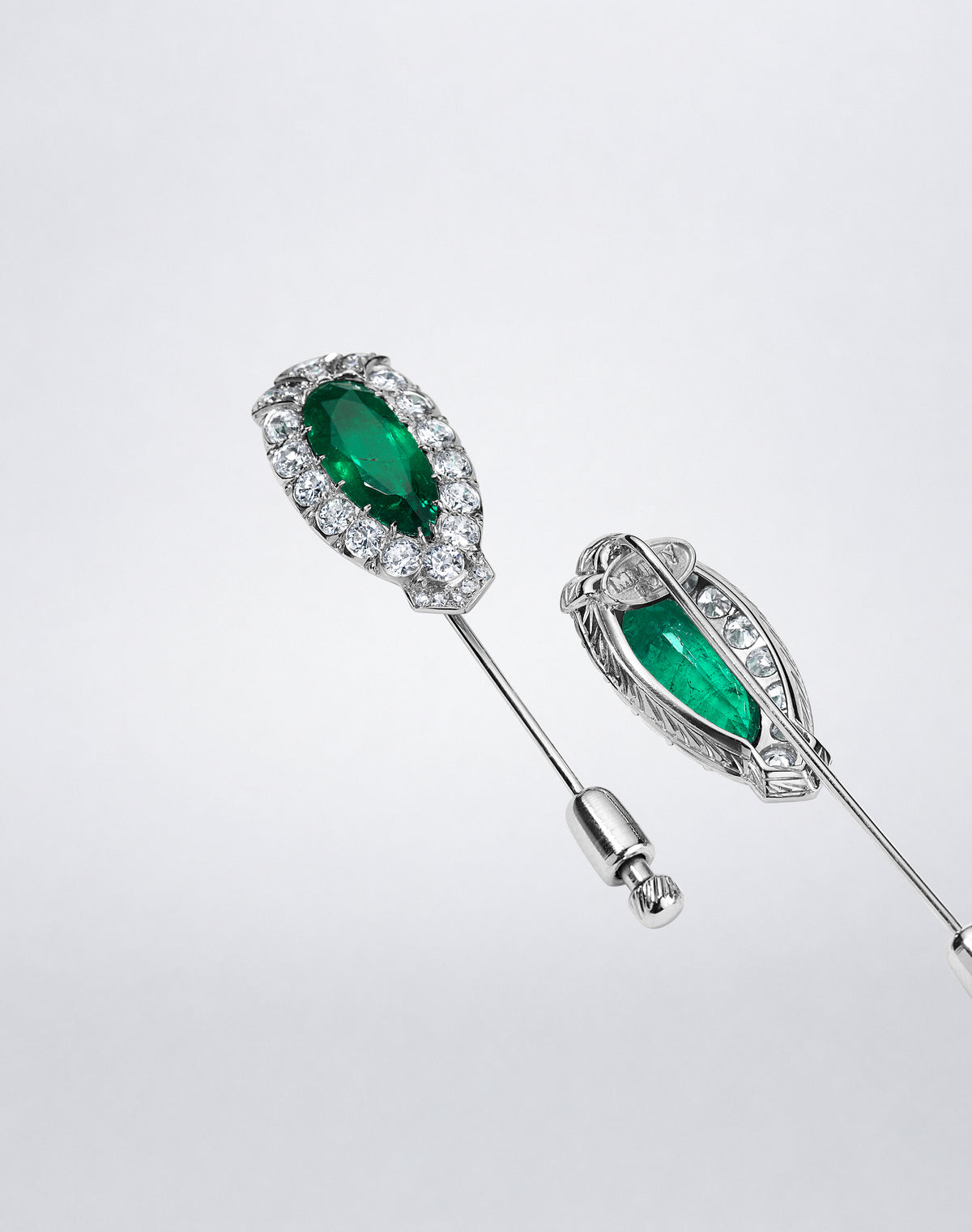 Angled front and back view of the one-of-a-kind Twin Colombian Emerald Pins, showing Colombian emeralds, diamond surrounds and stick pin backs in platinum. 